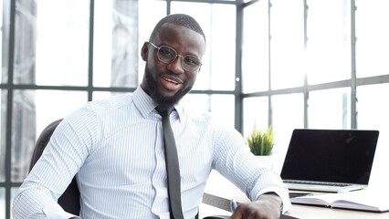 A businessman man in close-up in a shirt in the office looks at the camera