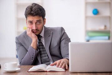 Obraz premium Young male employee reading book in the office