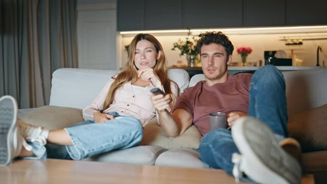 Young pair watching television switching channels couch. Couple choosing movie