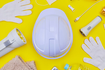 Safety helmet and disaster preparedness kit on yellow background.