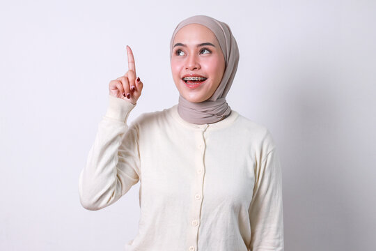 Young muslim woman looking and pointing up, showing got an idea gesture