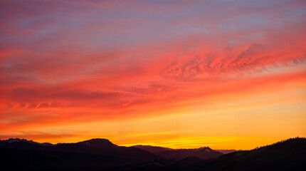 Fototapeta premium Vibrant Sunset Sky Over Silhouetted Hills 
