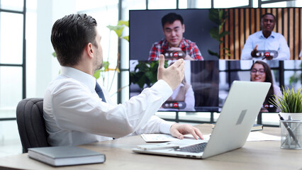 A male businessman is talking to colleagues at an online meeting