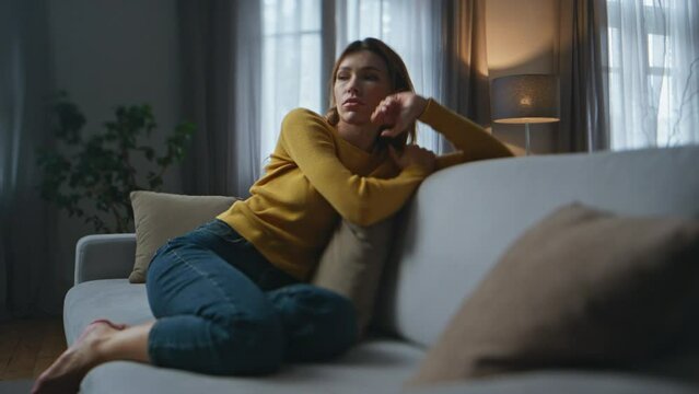 Apathetic woman feeling sleepy on sofa in living room. Lady looking distance