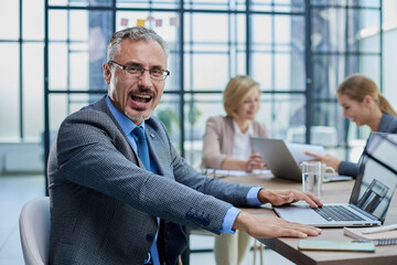 Happy businessman wearing eyeglasses sitting with laptop