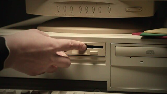 Using diskette FDD for old computer close-up. Hand inserting and ejecting Floppy Disk into vintage PC. Music recorder, playing retro computer games. 