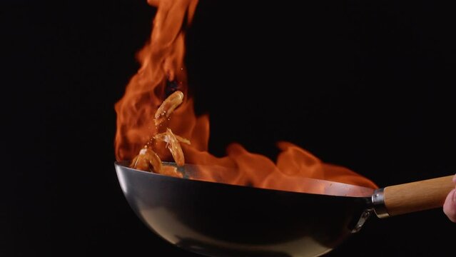 Chef cooking flambe shrimps with oil on wok frying pan close-up. Prawns on fire throwing them in pan. Restaurant Food concept. Sea food.
