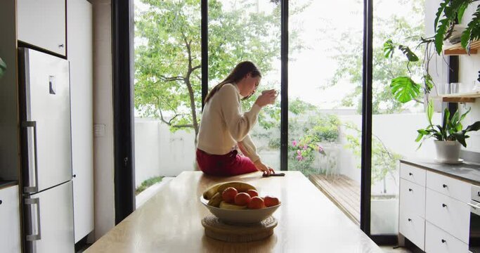 Young Caucasian transgender woman enjoys a beverage at home, with copy space