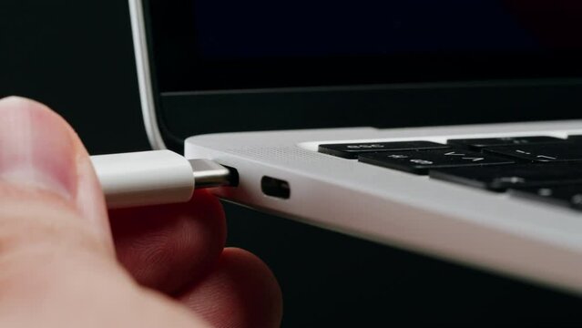 Charging connection to laptop on black background close-up . Phone charging port. USB wire for devices