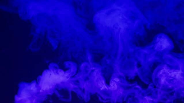 Smoke texture on black background in blue neon light. Smoking, steam clouds of vapour close-up. Burning, fog. 