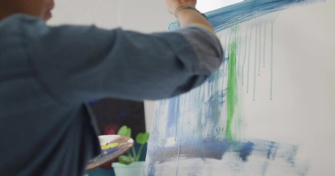 Artist paints on a canvas in a bright studio