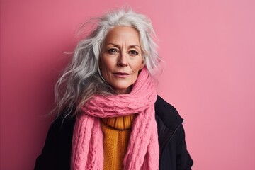 Portrait of a senior woman in winter clothes on a pink background