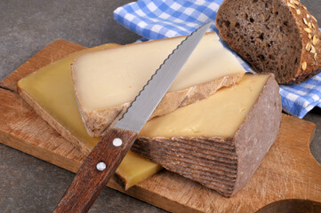 Assortiment de fromages sur une planche à découper avec un couteau et un morceau de pain en gros...