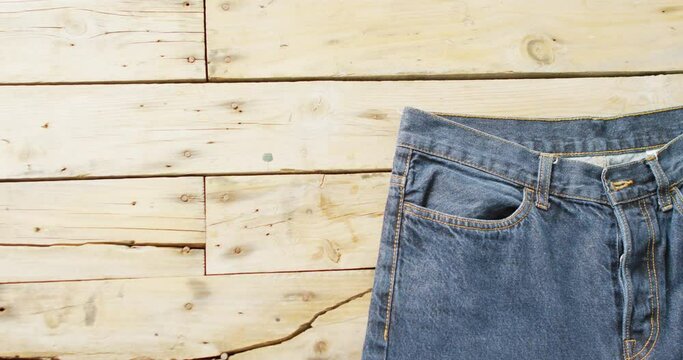 A pair of jeans lies on a wooden surface, with copy space