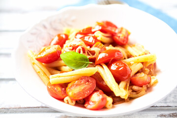 Casarecce pasta withe cherry tomatoes and fresh basil. Bright wooden background. Close up.	