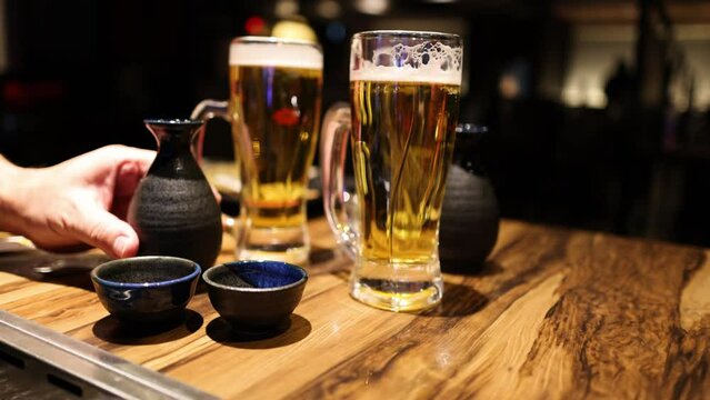 Pouring Sake into Cups Beside Beer