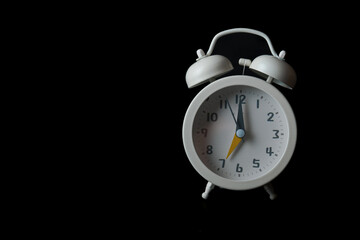 close-up of a white alarm clock isolated on a black background