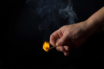 close-up of a woman's hand lighting a match isolated on black background