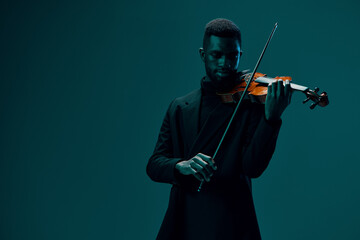 Elegant musician in black suit performing with violin against vibrant blue background
