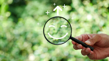 Hand holding a magnifying glass highlighting a happy smile. Concept of positive thinking, mental...