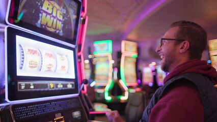 A delighted male gamer celebrating a win at a slot machine in a casino environment, celebrating his luck in hotel, Big Win, Las Vegas, USA. Slow Motion, Camera 4K RAW. 