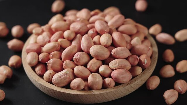 closeup of peeled raw peanut kernel on black background.