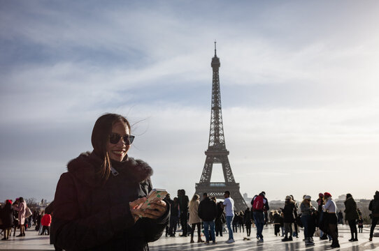 Asian woman using the mobile phone in front of the Eiffel tower, Paris, France