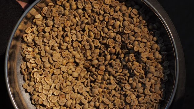 Production of fresh fried coffee. Beans falling into funnel. Preparation fresh caffeine on manufacturing warehouse. Coffee in large roaster falling beans. Coffee roaster machine mixing aroma beans
