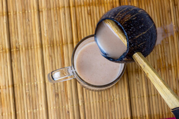 Pouring traditional African sorghum beer in a mug using a local scoop