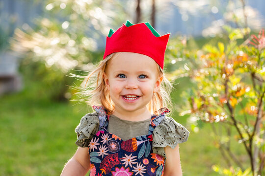 Portrait of a happy toddler girl outside in felt Christmas cracker hat