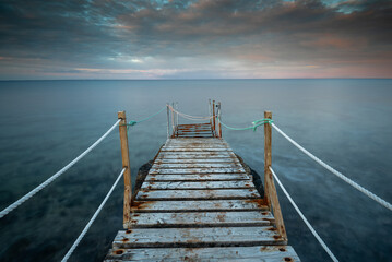 Long wooden pier in the sea at sunset.