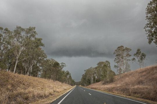 looking down an empty highway towards storm clouds