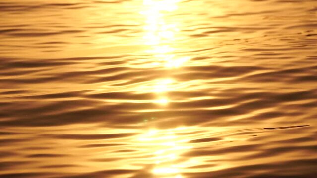 Sea water surface sunset. Low angle view over golden sea water. Sun glare. Abstract nautical summer ocean nature. Holiday, vacation and travel concept. Nobody. Slow motion. Weather and climate change