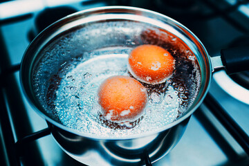Stainless steel saucepan with boiling eggs for breakfast in boiling water on gas stove top view. - 738591105