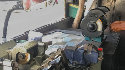 Locksmith Workshop with Tools and Machinery. Locksmith's workbench with various tools, key-cutting machine, and vice in a workshop setting.