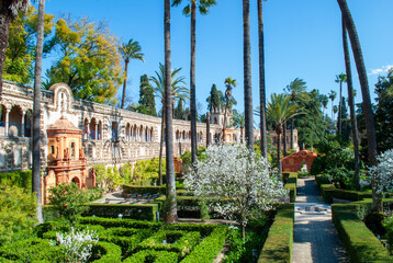 the splendid Mudejar architecture represented by the flower gardens of the Real Alcazar of Seville in Andalusia - obrazy, fototapety, plakaty