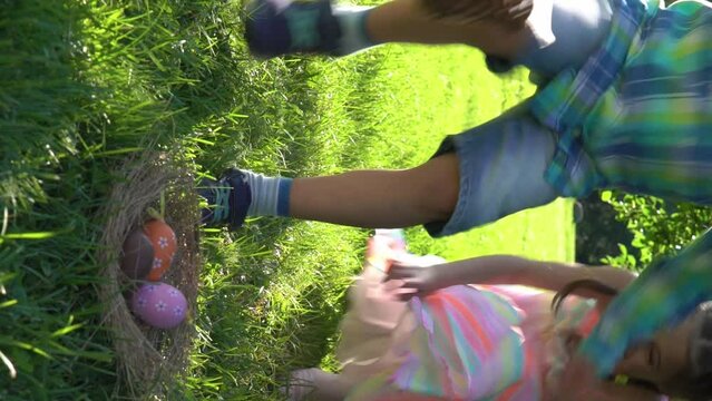 Two children boy and girl having easter egg hunt in garden backyard