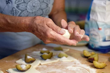 Foto op Canvas Preparation of homemade fruit dumplings with plums. Czech specialty of sweet good food. Dough on kitchen wooden table with hands. © montypeter