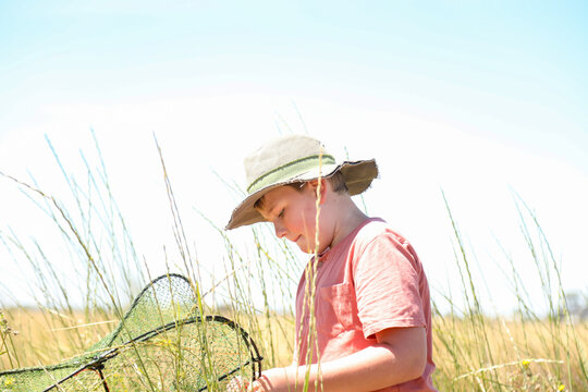 Teen boy casting yabby net into channel on rural property