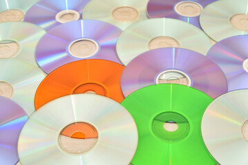 Pile of multicolored CDs and DVDs on the brown wooden table. Vintage technology concept. Selective...