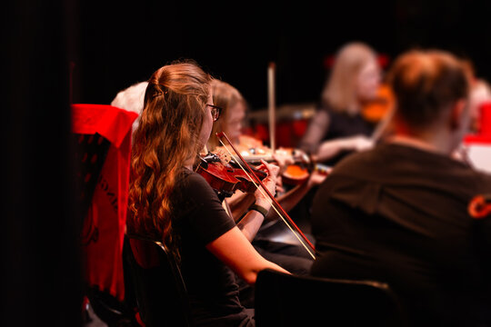 Violinist playing in strings section at music concert