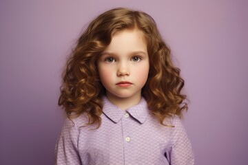 Cute little girl with long curly hair. Studio portrait over purple background.