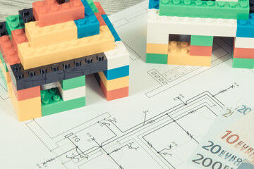 Small houses made of toy blocks, housing plan with electric installation and euro banknotes....