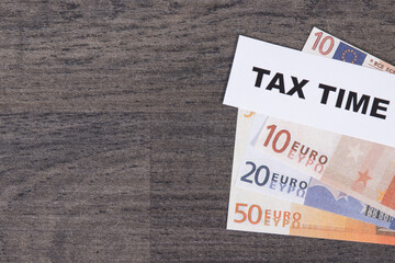 Inscription tax time and euro banknotes. Calculating and paying tax. Place for text