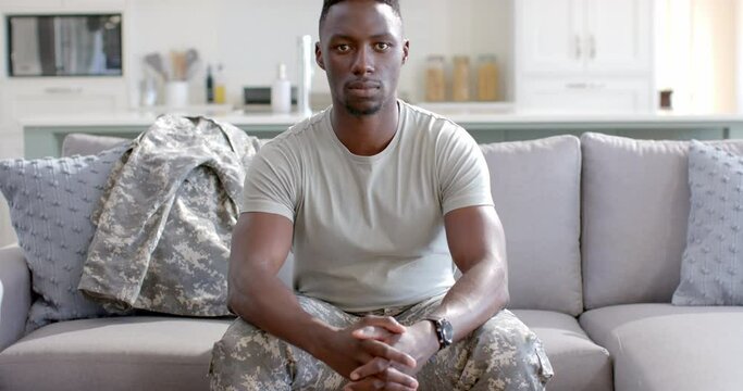 Young African American soldier sits confidently at home, with copy space