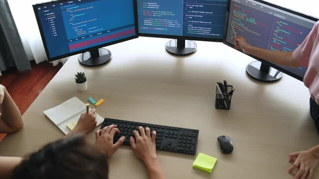 Slow motion back end software developer engineer for computer programming working together on debugging writing computing code, solving complex algorithms display on monitor in office. Burgeoning
