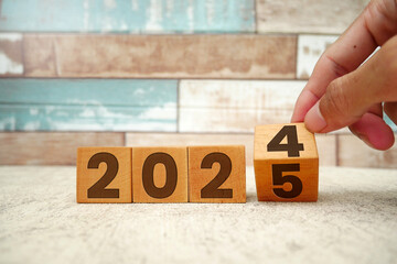 Hand flipping block 2024 to 2025 text on table. Resolution, time, plan, goal, motivation, reboot,...