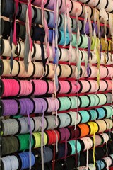 Fototapeta premium Bobbins with various colorful ribbons on counter in store. Needlework and sewing supplies. Colorful ribbon on rack in craft shop. Artisan and handicraft material. DIY hobby concept