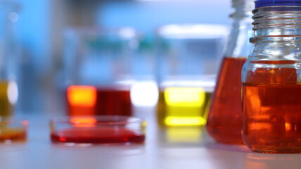 Scientists are doing research in a science lab. A medical chemist in a white coat, gloves and goggles looks at a glass tube. Compare two different liquid samples. and discuss future experiments.