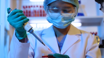 Scientists are doing research in a science lab. A medical chemist in a white coat, gloves and...